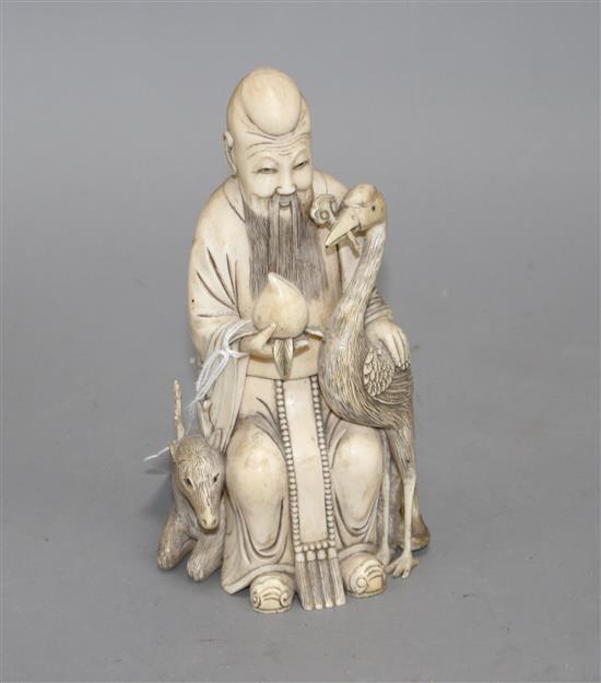 A Chinese carved ivory group of a sage holding a peach, seated beside a crane and a deer, 17cm